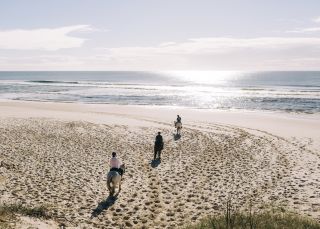 Group enjoying a horse-riding experience along Tyagarah Beach with Zephryr Horses in Byron Bay