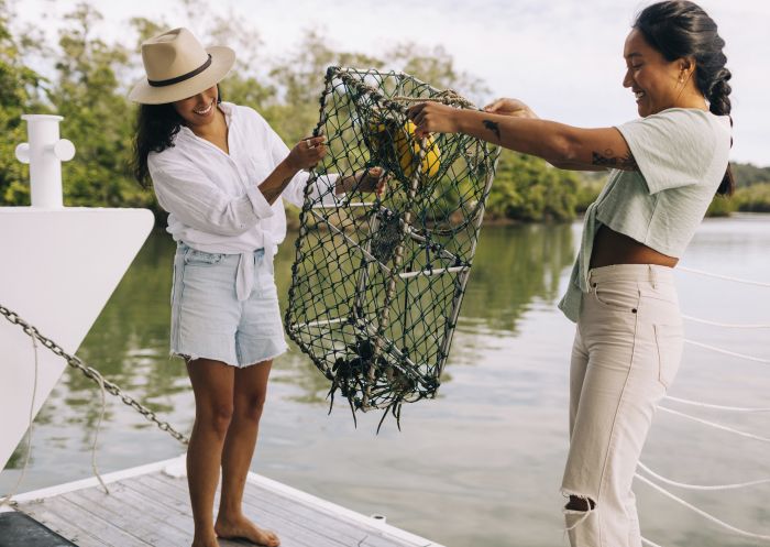 Women holding their catch during a Catch A Crab boat tour on the Tweed River, West Tweed Heads