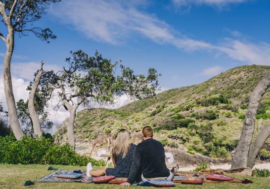 Couple enjoying a romantic picnic set up by Fuller Food Co. at Little Bay Picnic Area, South West Rocks, Macleay Valley Coast, North Coast